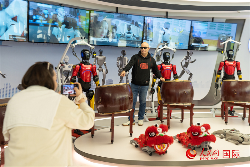 人民网外专亚瑟夫在深圳玉树具身机器人智创中心的打鼓机器人前拍照留念。人民网记者许峥摄